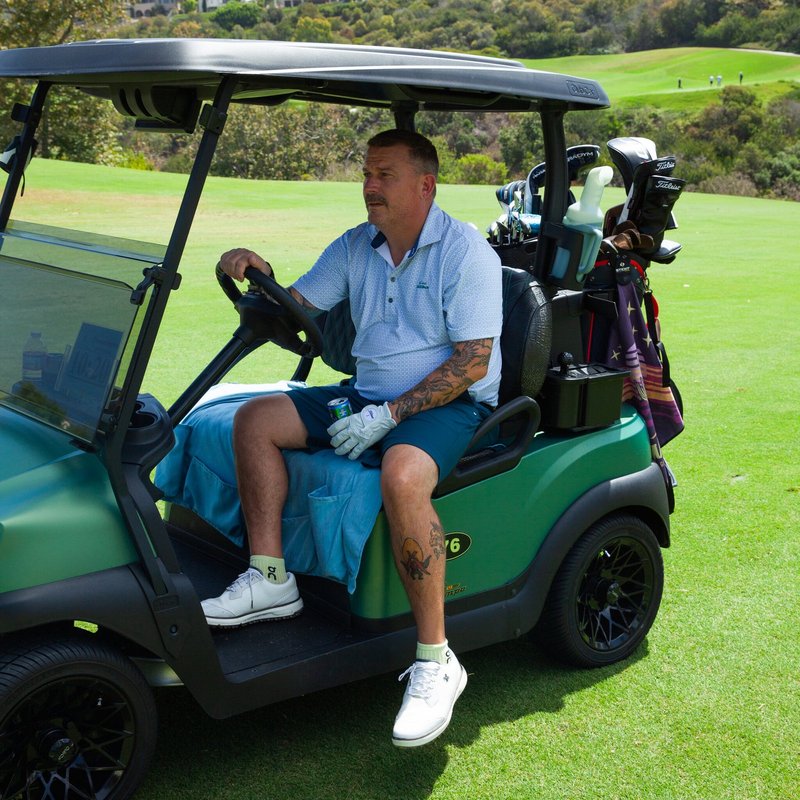 Golfer seated on the Caribbean Blue seat cover in a golf cart